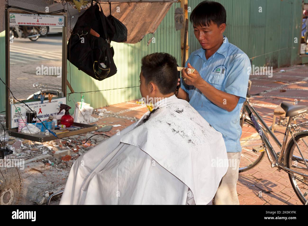 Barber and customer in open air barber shop, Hai Phong, Vietnam Stock Photo