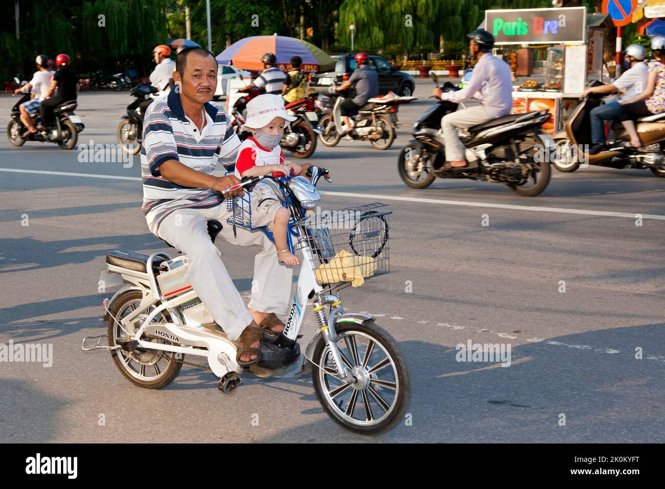 Man carrying baby on electric bicycle in traffic, Hai Phong, Vietnam Stock Photo
