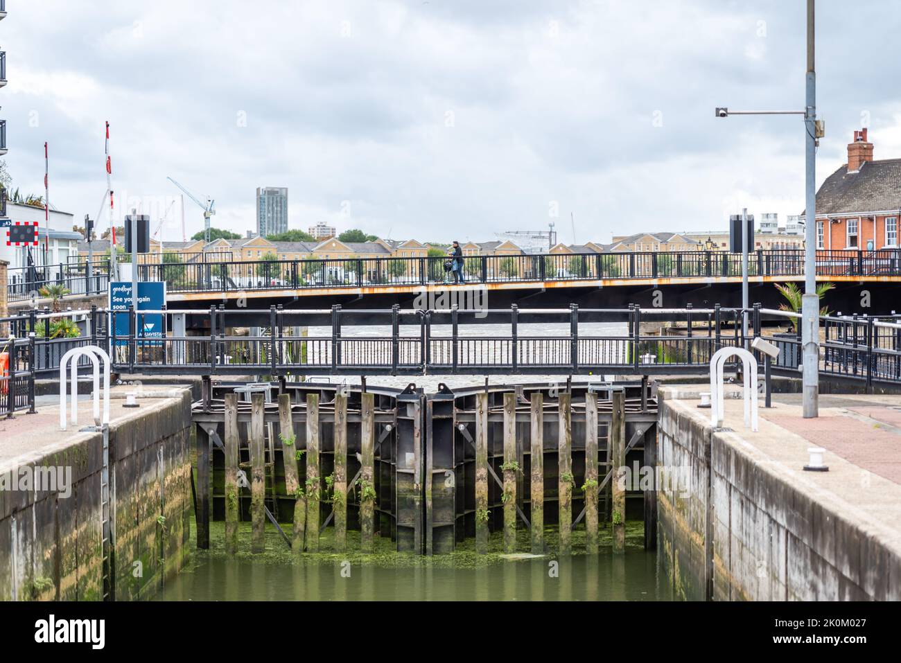Person cycling across Limehouse Basin Lock in London, UK Stock Photo
