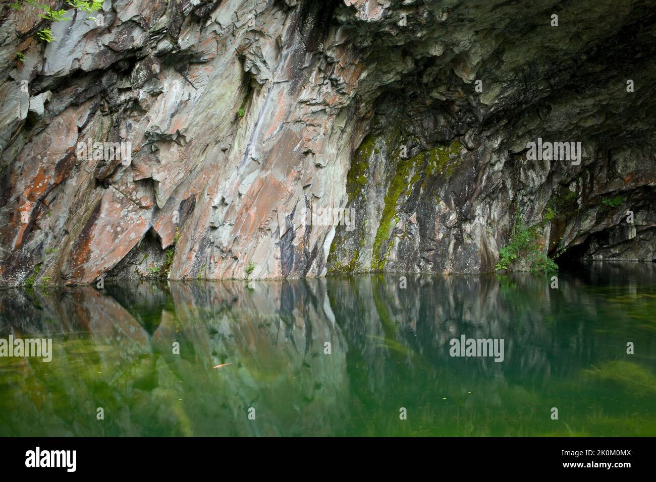 Slate reflected in the waters of a cave, part of a disused quarry, by Rydal Water in the Lake District, England, UK Stock Photo