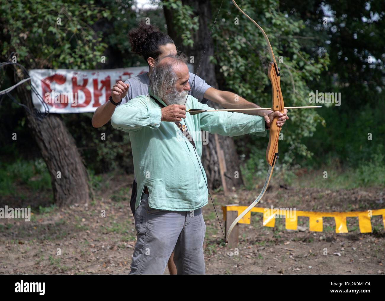 Belgrade, Serbia, Aug 27, 2022: Retired man having archery lesson Stock Photo