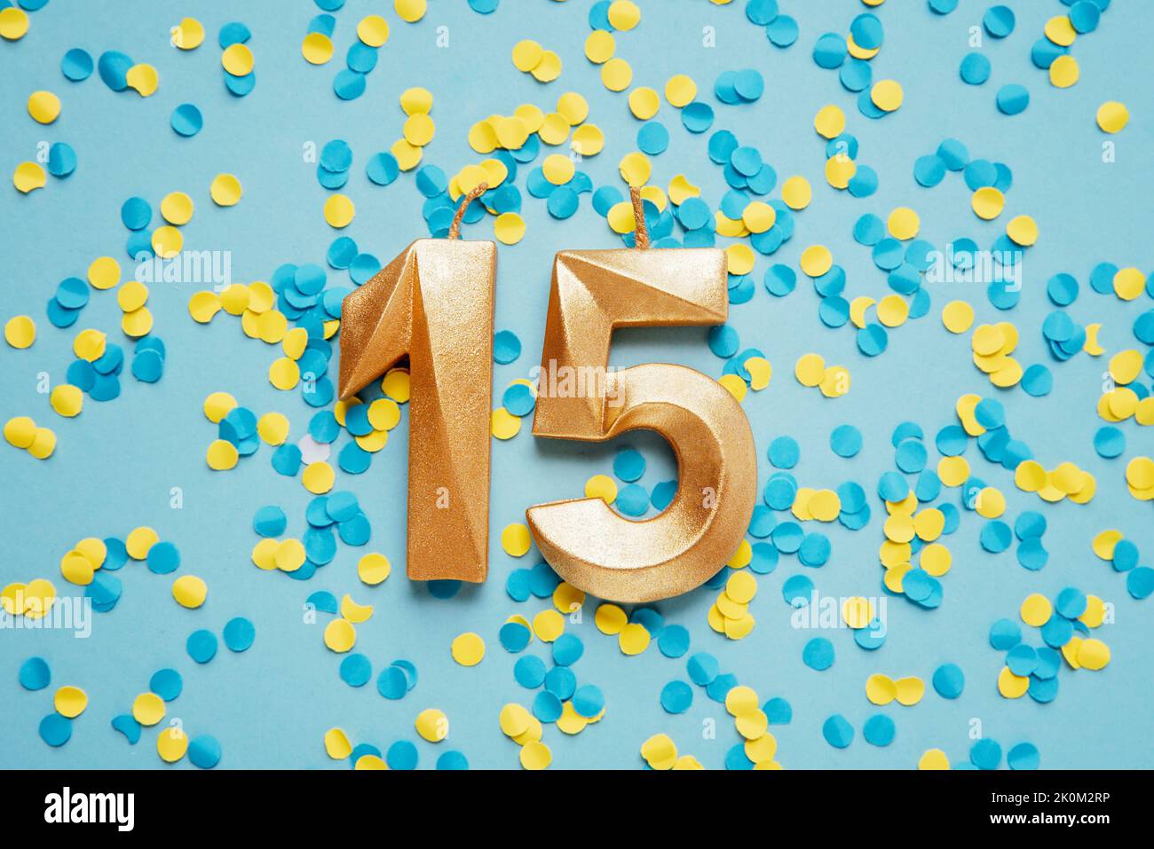 Number 15 fifteen golden celebration birthday candle on yellow and blue Number 15 fifteen golden celebration birthday candle on yellow and blue
