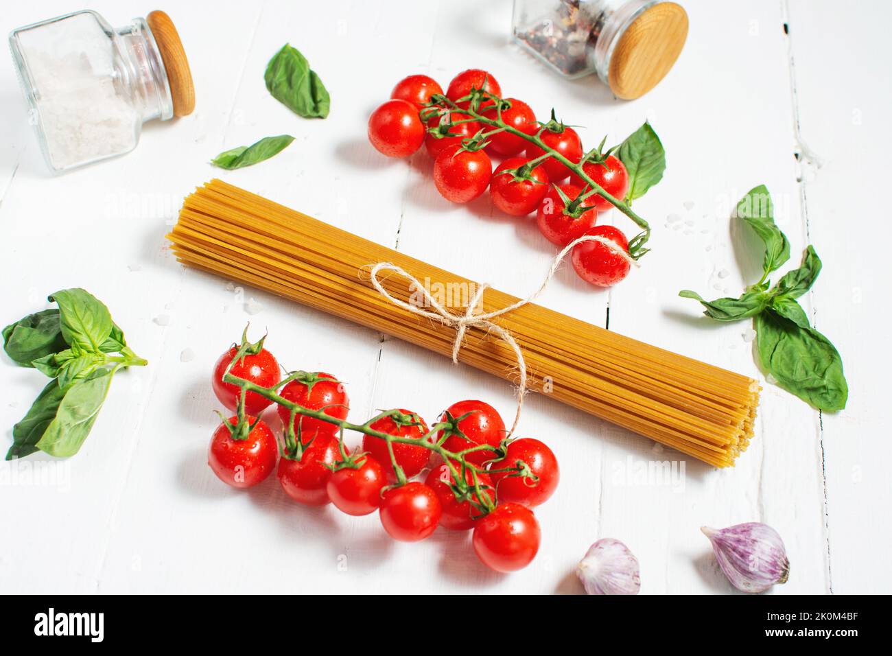 Spaghetti, basil and tomatoes isolated on a white wooden table. Stock Photo