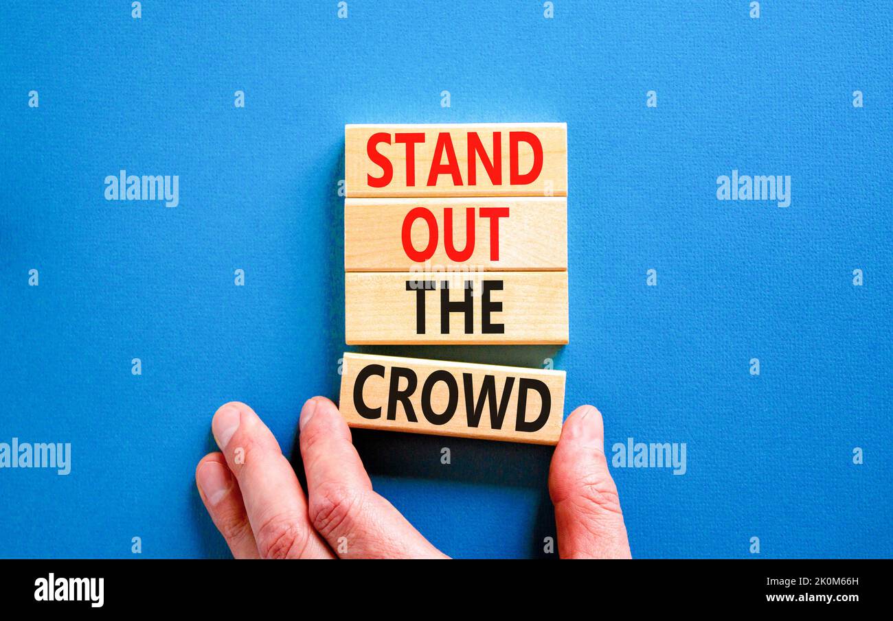 Stand out the crowd symbol. Concept words Stand out the crowd on wooden blocks on beautiful blue