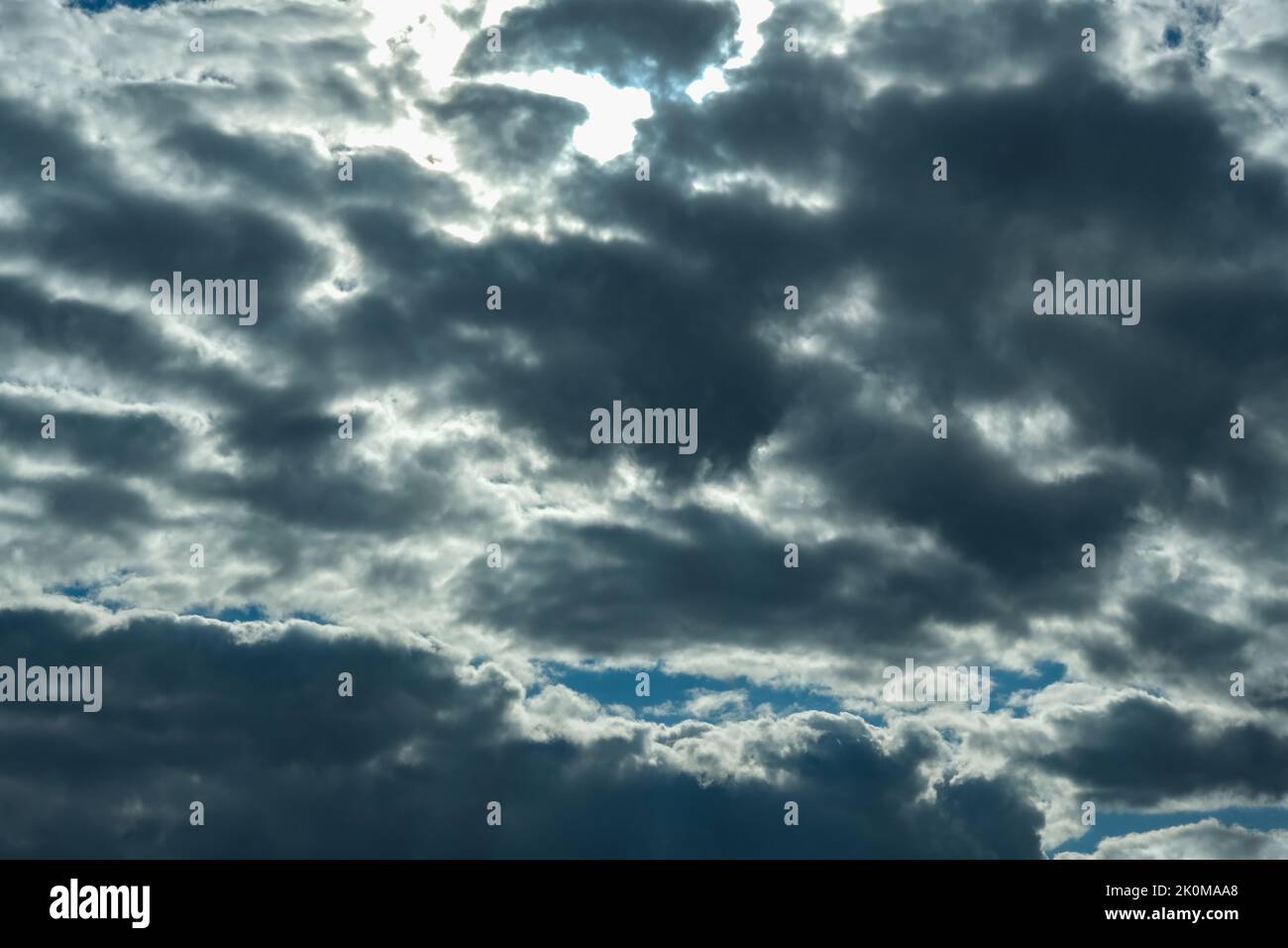 Blue sky with thunderclouds. The sun breaks through the clouds. Black clouds. Stock Photo