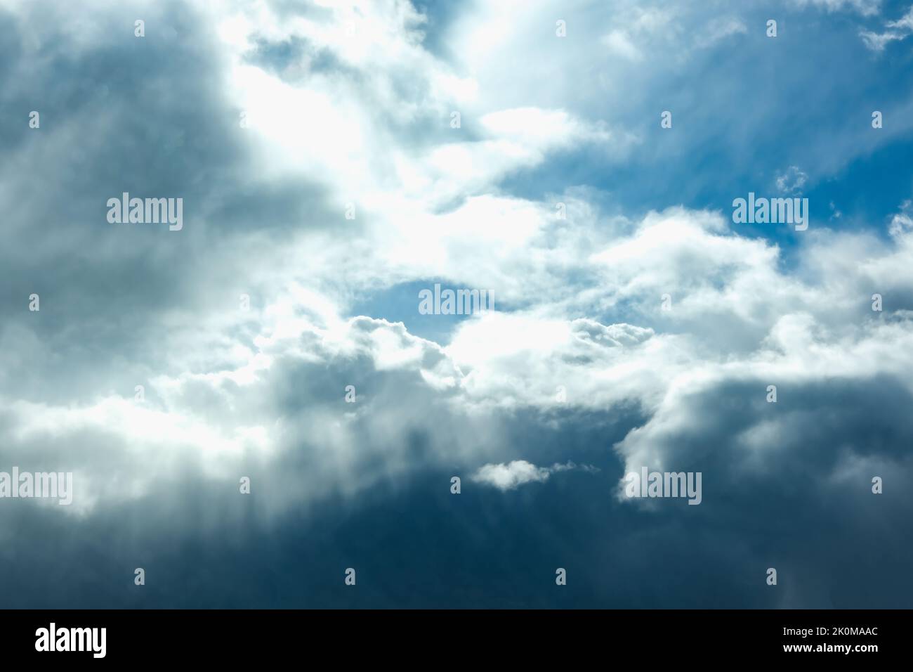 Blue sky with thunderclouds. The sun breaks through the clouds. Black clouds. Stock Photo