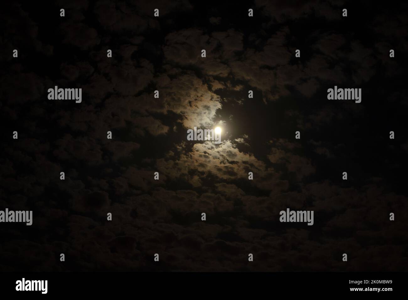 Close up night photo of full moon on cloudy sky. Stock Photo