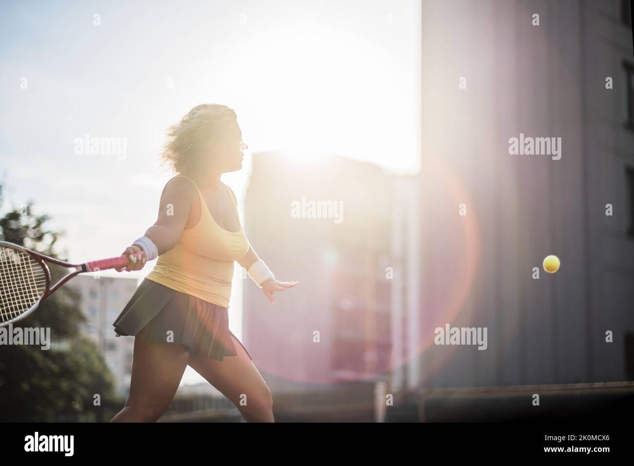 Caucasian mature woman playing tennis outside. Active hobby outdoor Stock Photo