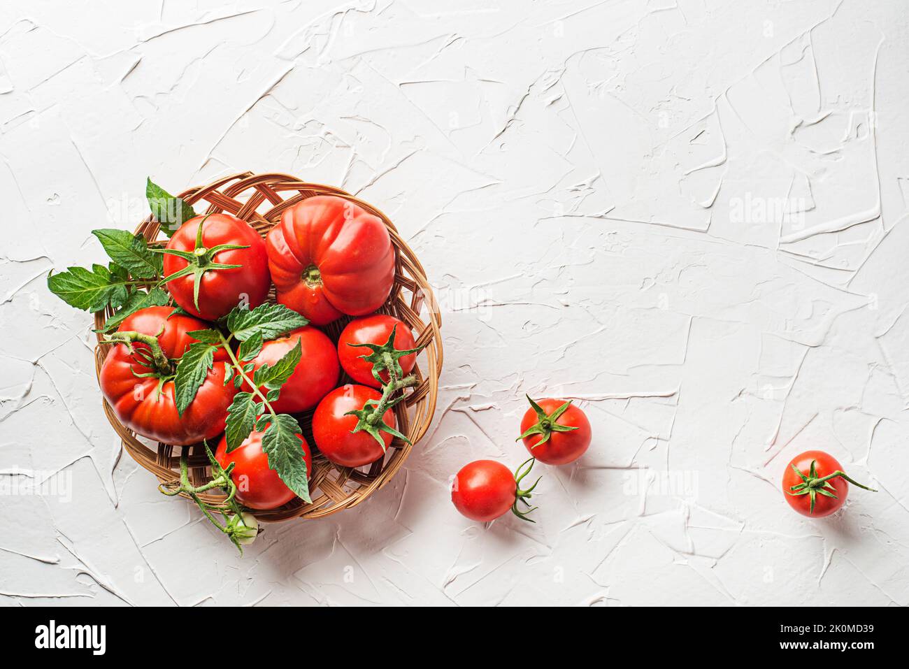Fresh tomatoes in basket on white table background. Harvesting tomatoes. Top view Stock Photo
