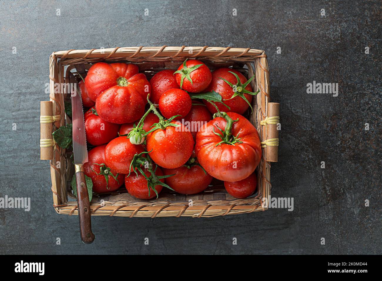 Fresh tomatoes in basket on dark background. Harvesting tomatoes. Top view Stock Photo