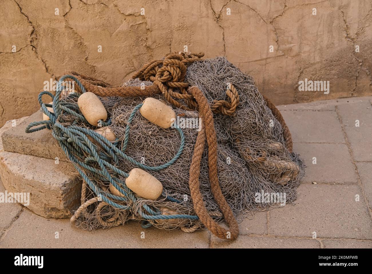 Heap of fish mesh traps on wall background. Braided fishing net from fibers woven in a grid-like structure with floats. Stock Photo