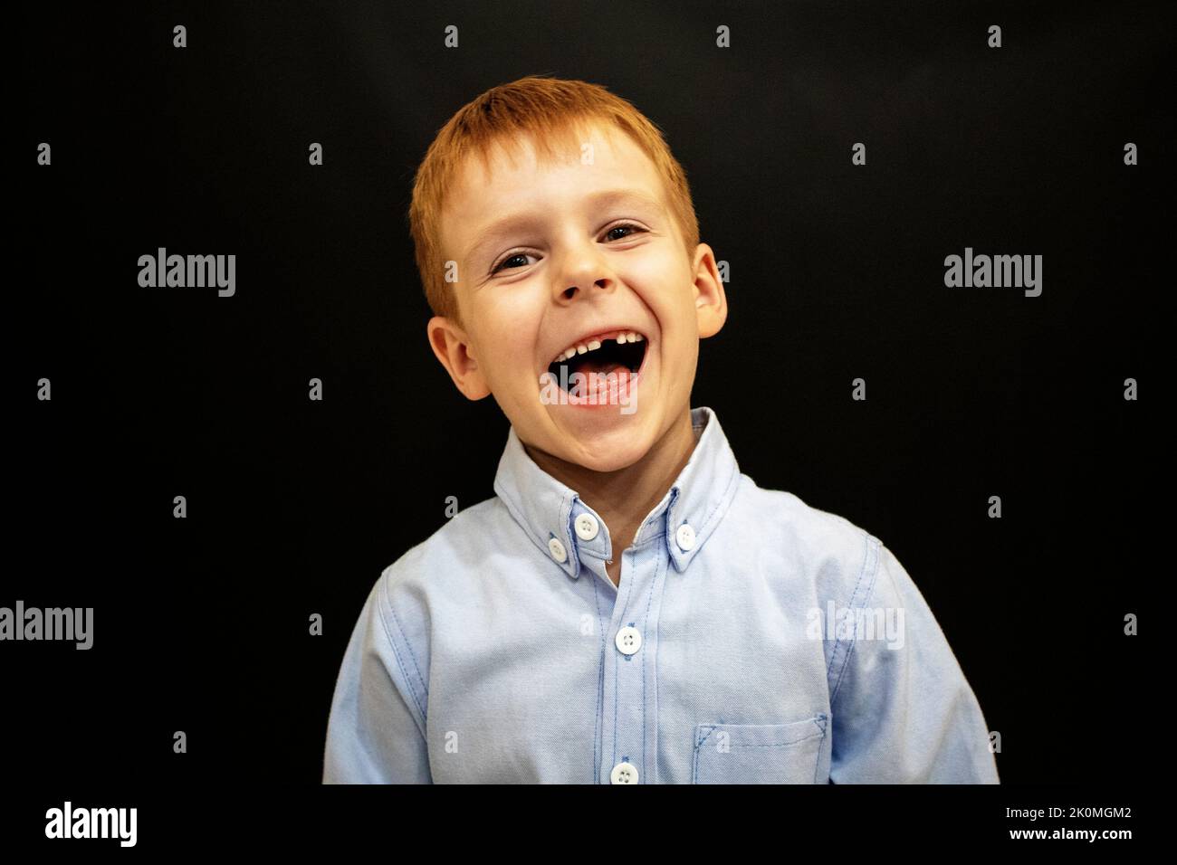 a happy little boy in a shirt on a black background Stock Photo Alamy