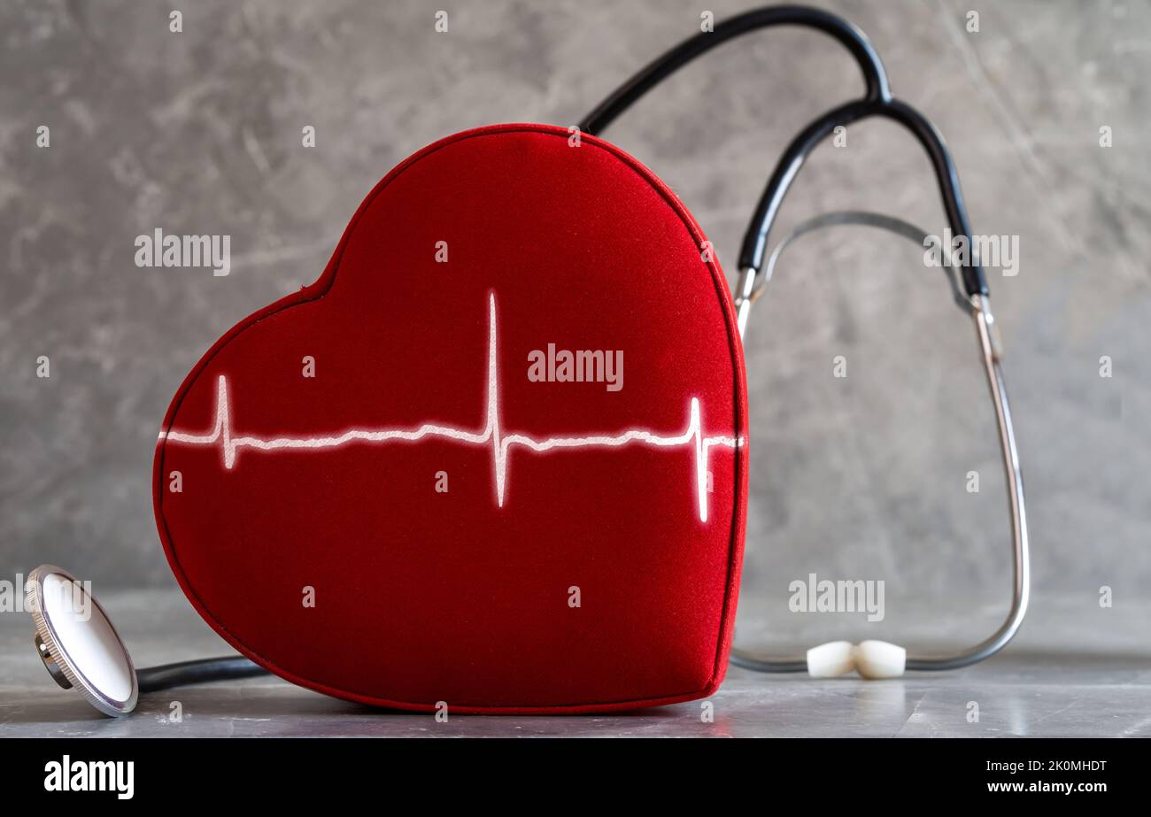 Close up photo of red heart, stethoscope and heart rate graph in the same frame. Concept of cardiovascular health and illnesses. Stock Photo