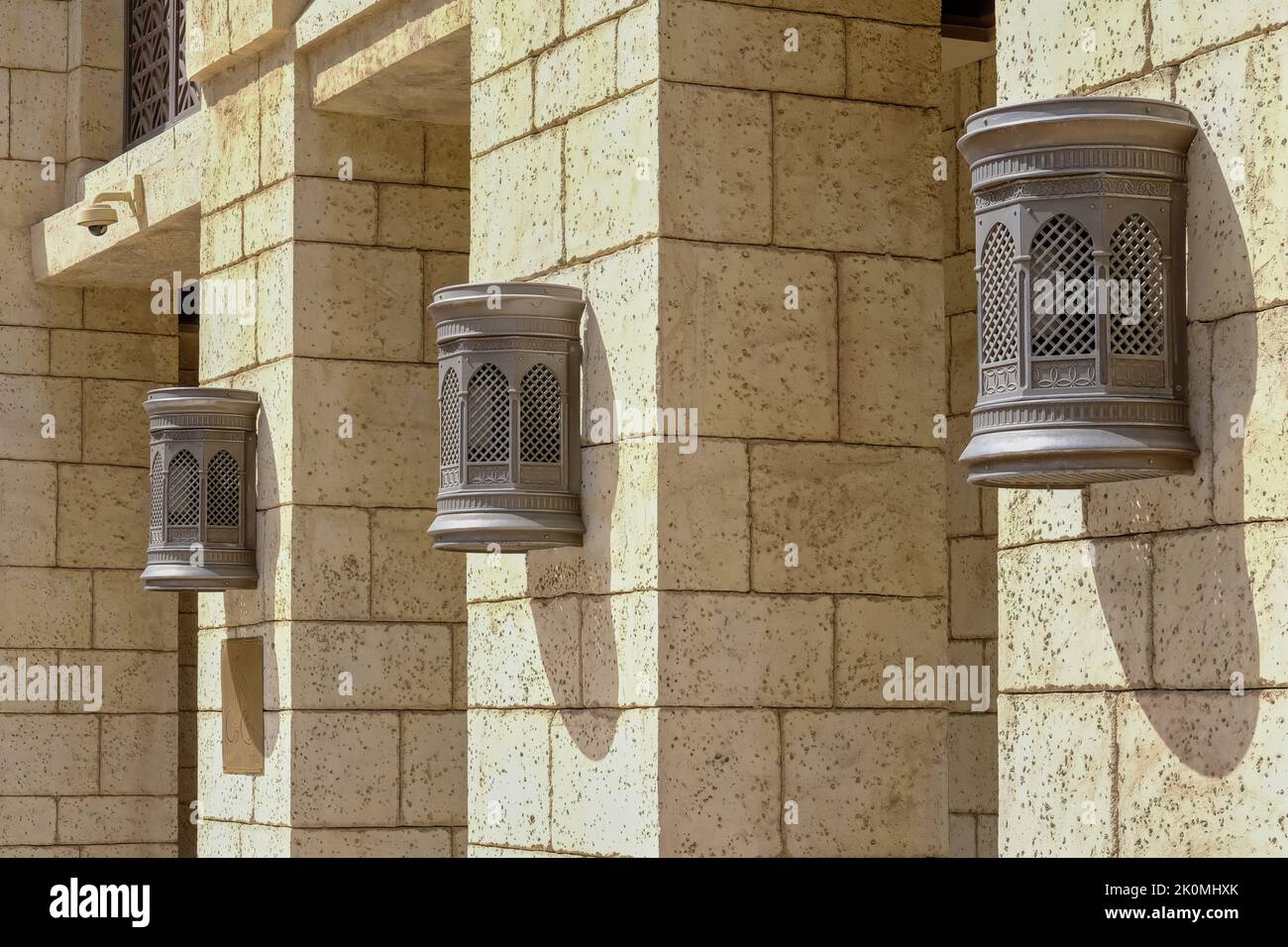 Vintage-style Arabic wall lamps and metal lanterns with traditional perforated orient design on villa or palace facades Stock Photo