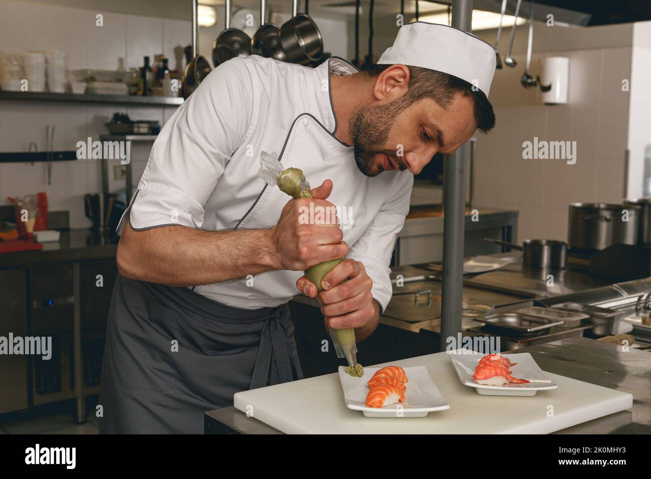 Handsome Male Chef in uniforms preparing sushi in a kitchen of asian restaurant Stock Photo