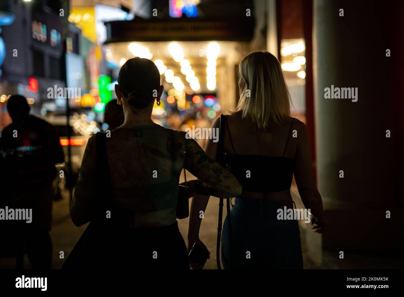 Two women walking on a sidestreet in the nighttime Stock Photo - Alamy