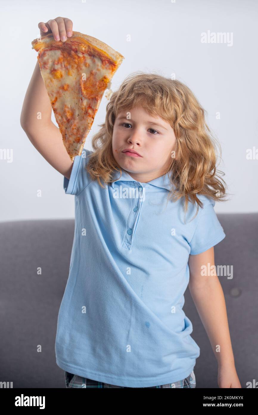 Child boy eating pizza. Funny kid holding pizza slice near face Stock