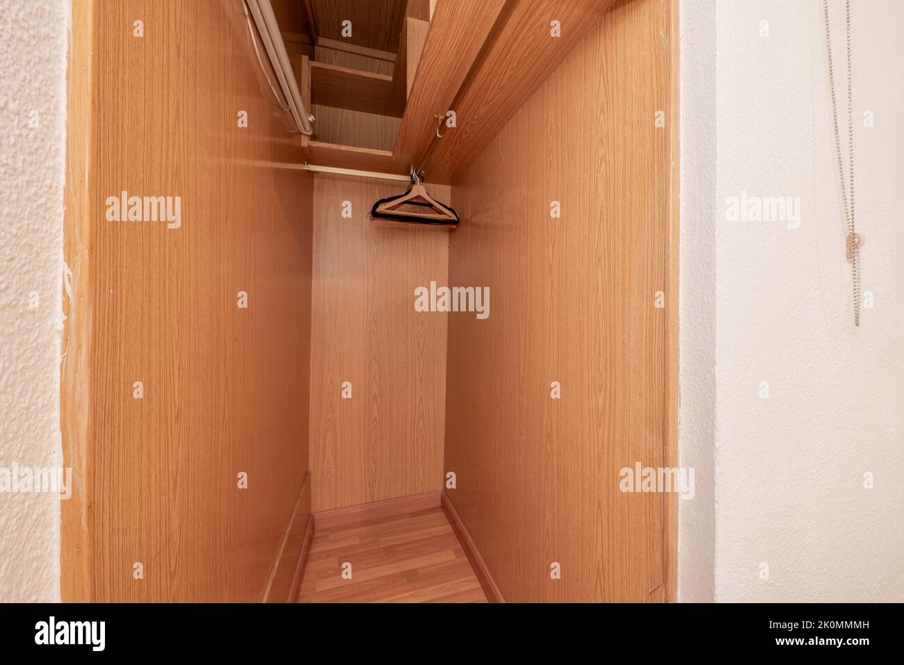 Small space used as a closet with shelves, hanging bar and hangers Stock Photo