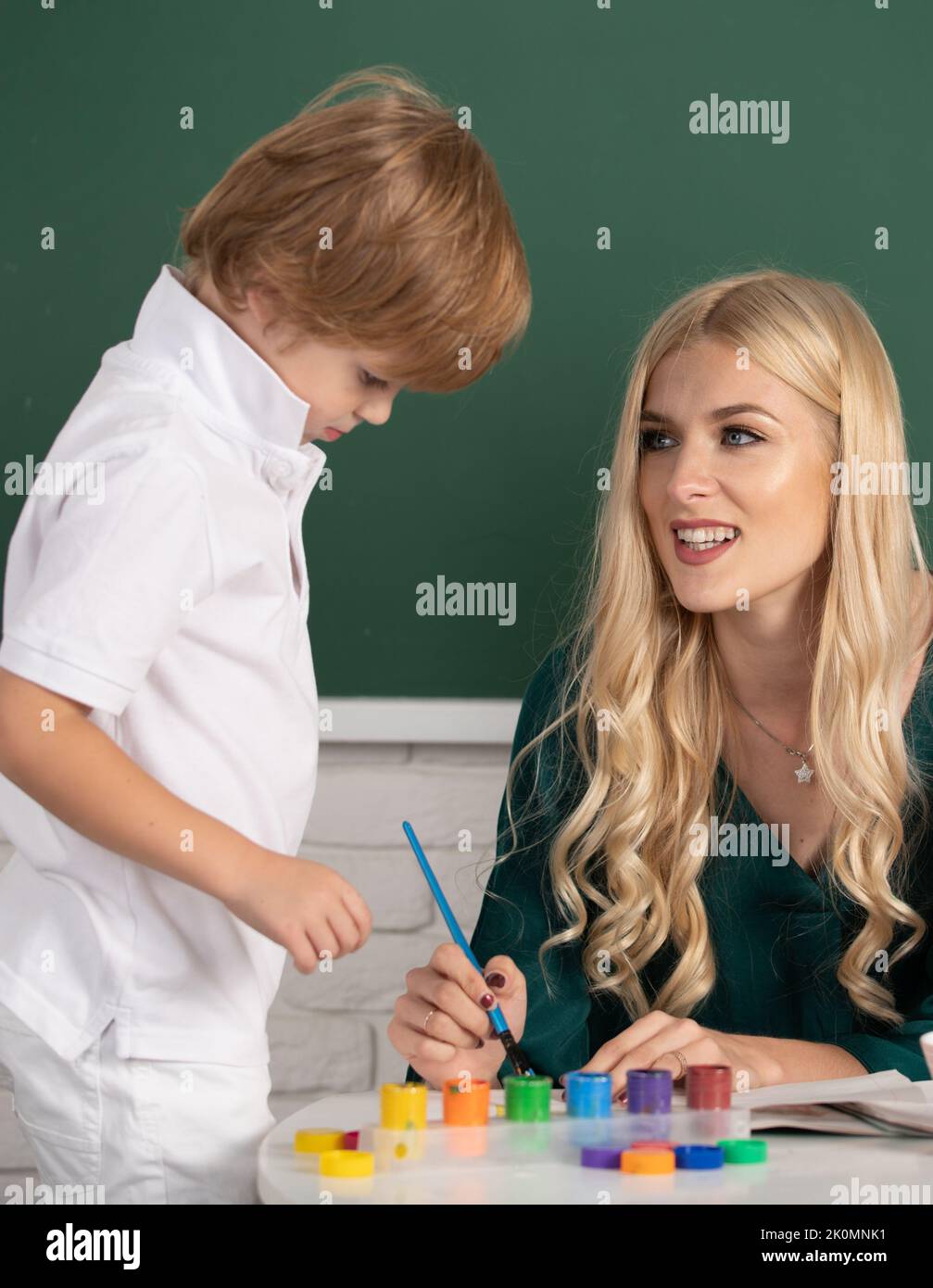 Mother and two son together draw, paint. Mom helps the child boy