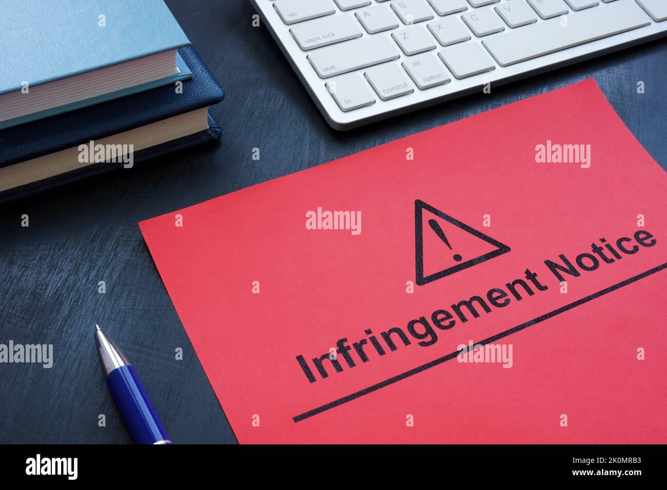 Infringement notice near a keyboard and notepads. Stock Photo