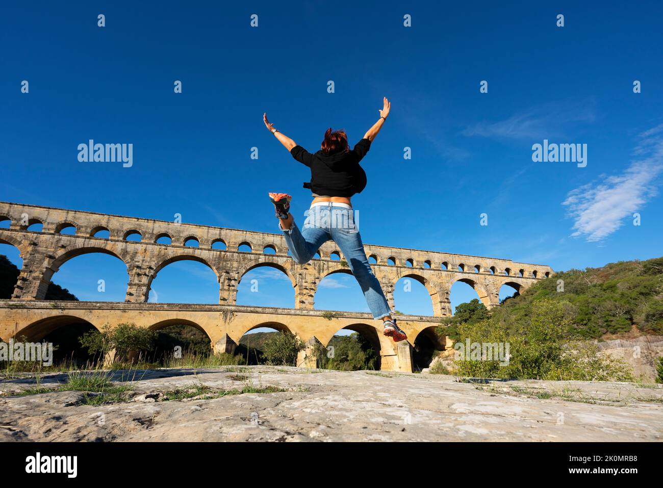 View of Woman jumping in front of Pont du Gard, France, Europe Stock Photo
