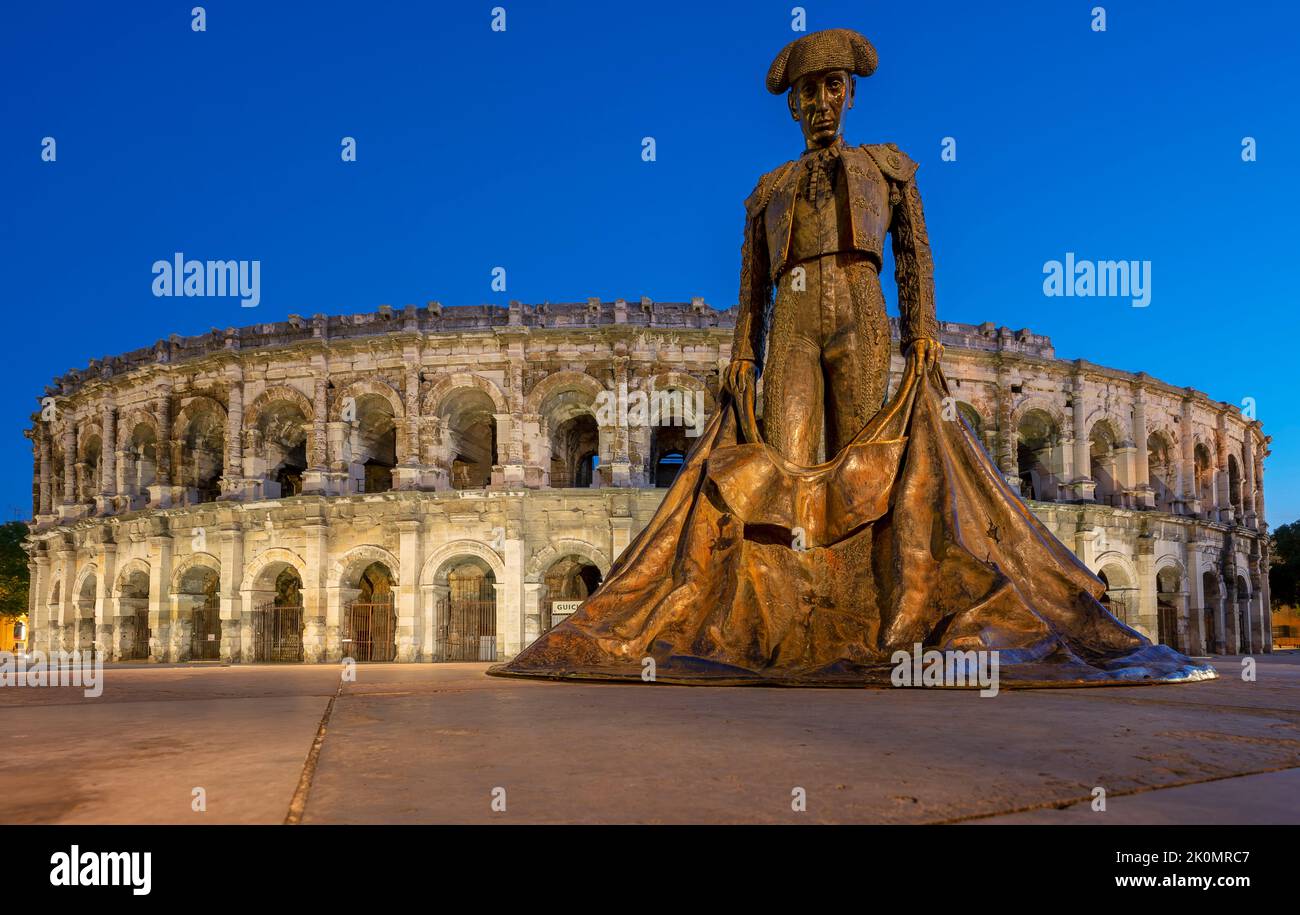 View of famous arena and statue, by night, Nimes, France Stock Photo