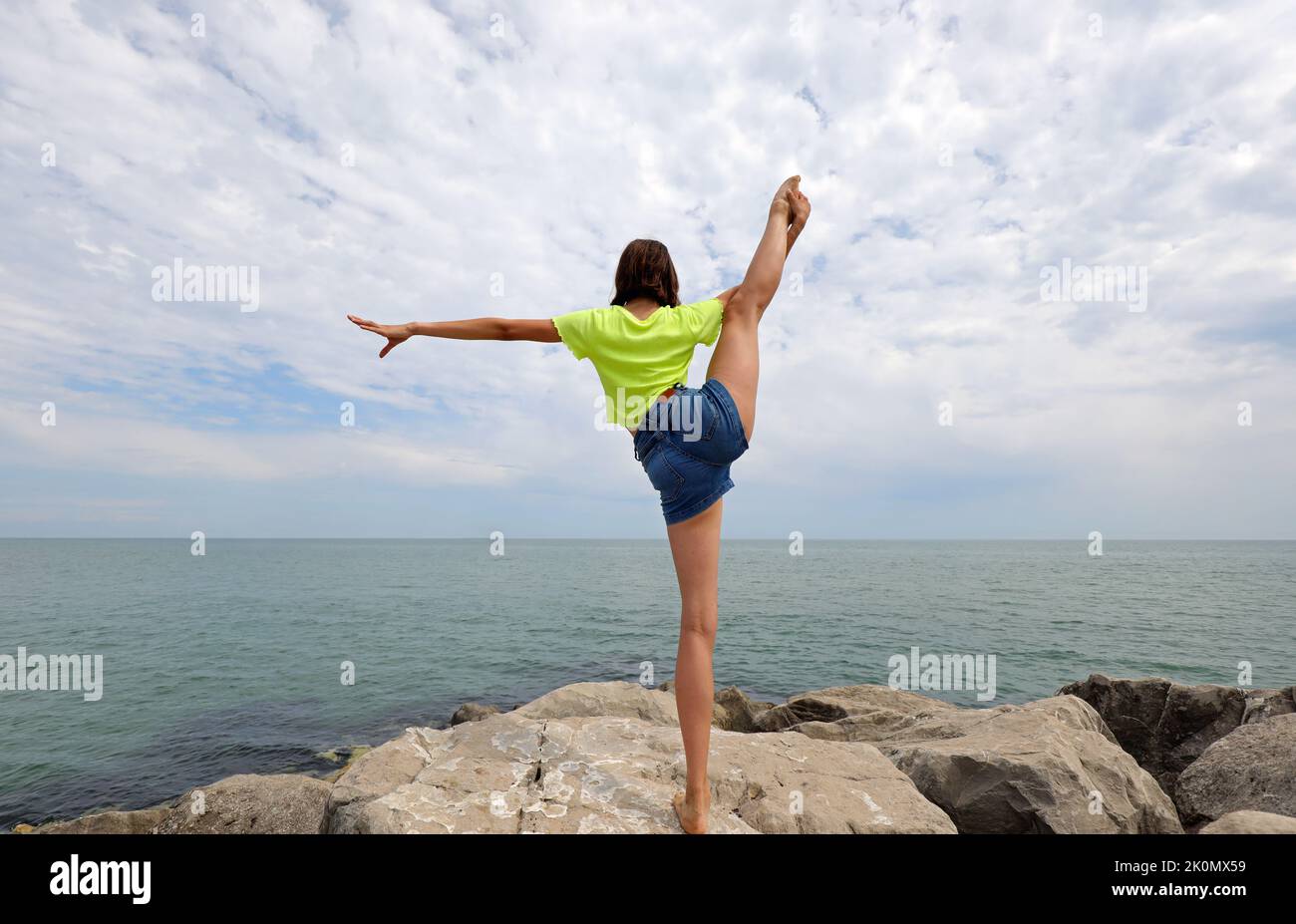 young girl does gymnastic exercises to train her balance by stretching ...