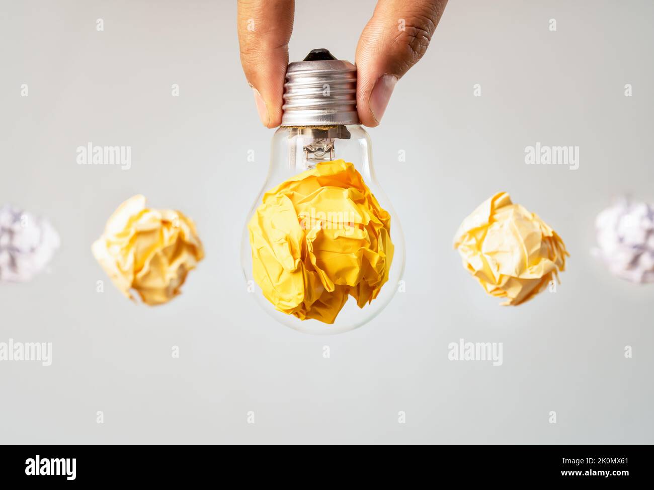 Close up photo of crumbled colorful paper and light bulb in the same frame as a symbol of persistance, perseverance and hardwork. Stock Photo