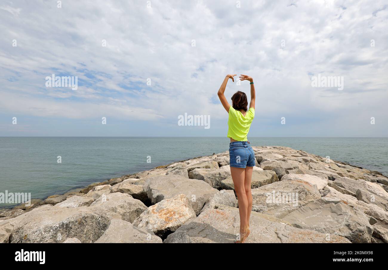 balance exercise on the cliffs by the sea performed by a girl from the