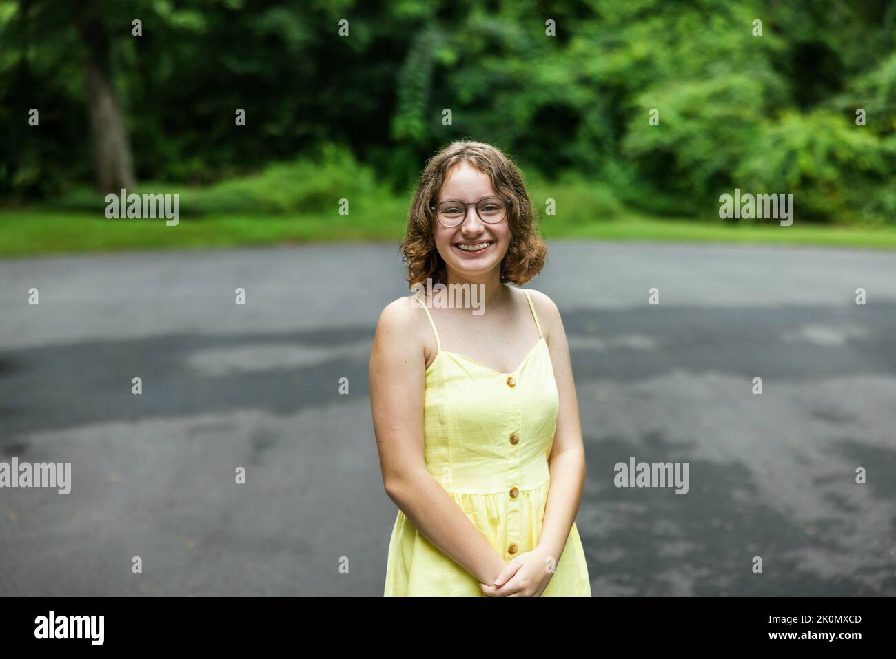 Tween almost teenage girl with braces and wearing a yellow sundress outside in the summer. Stock Photo