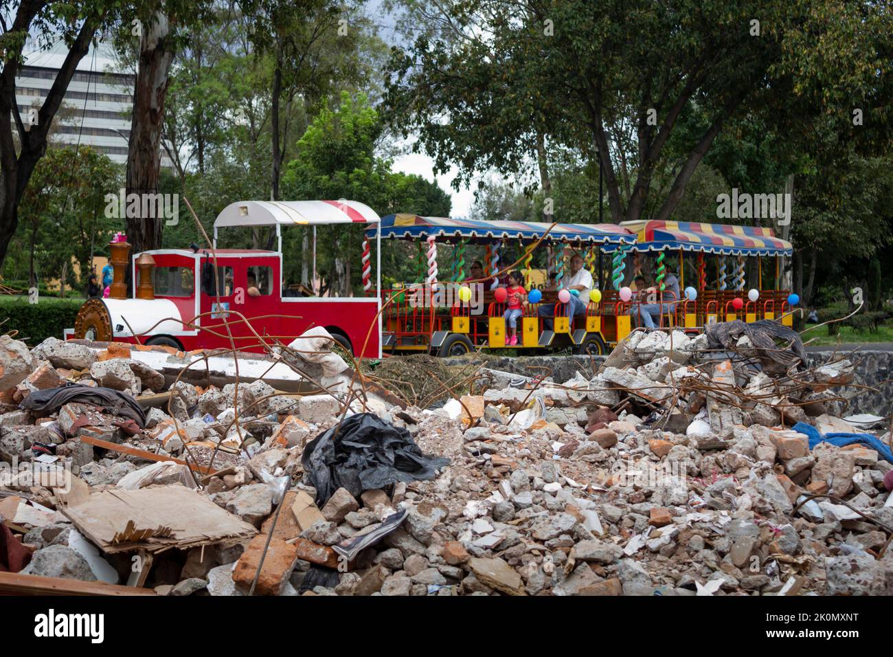 People riding a park train looking at building debris. In 2017, an 8.1 ...