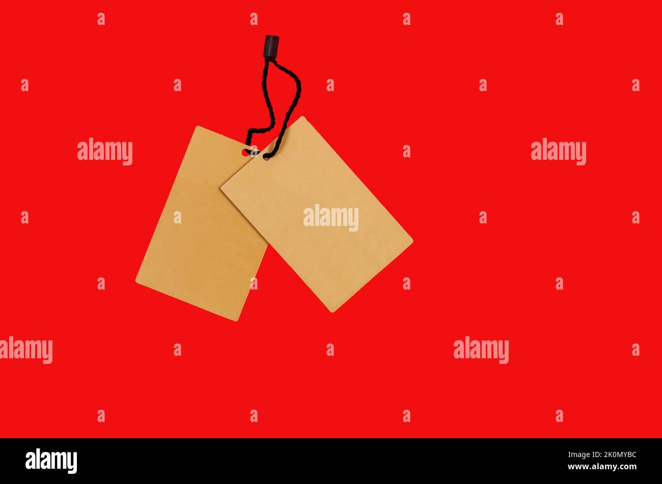 Empty brown cardboard tag with string on red background. Vintage paper textured tag. Mockup cardboard label. Price tag, gift tag, sale tag, address la Stock Photo