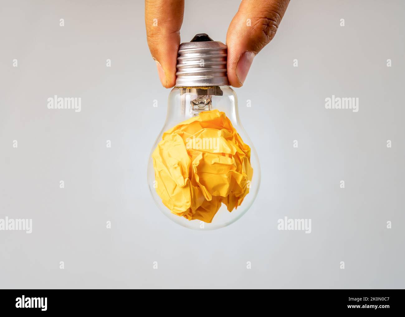 Close up photo of crumbled colorful paper and light bulb in the same frame as a symbol of persistance, perseverance and hardwork. Stock Photo