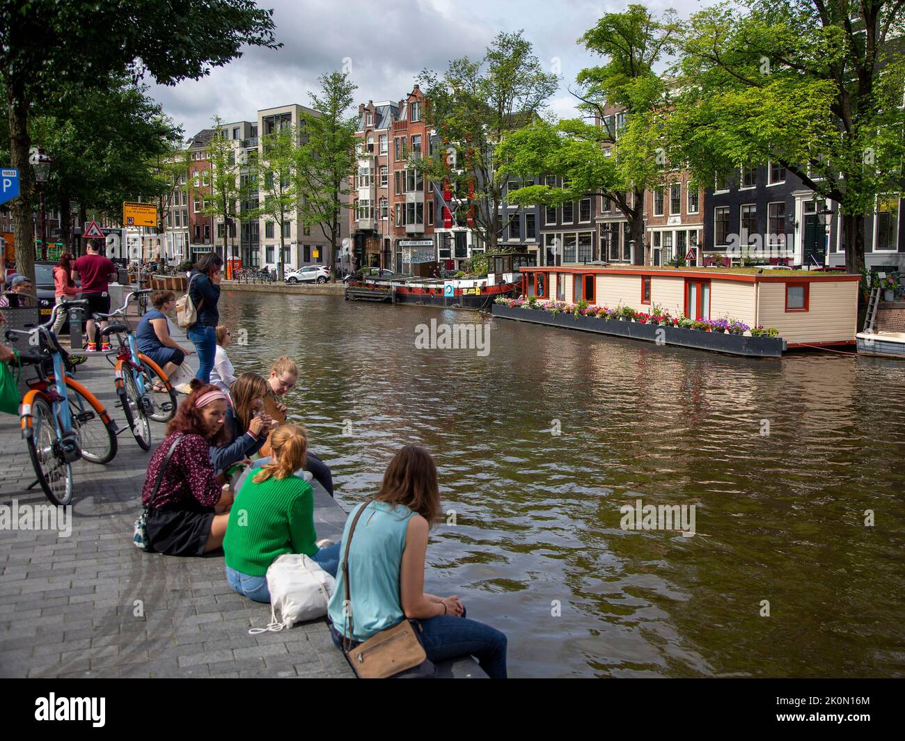Students sitting beside an Amsterdam canal Stock Photo