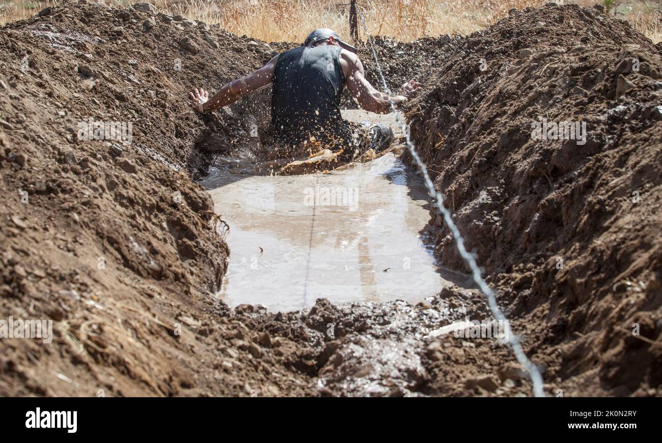Merida, Spain - Sept 11th, 2022: FarinatoRace Merida 2022. Toughest obstacle course in the world. Trench flooded with barbed wire Stock Photo