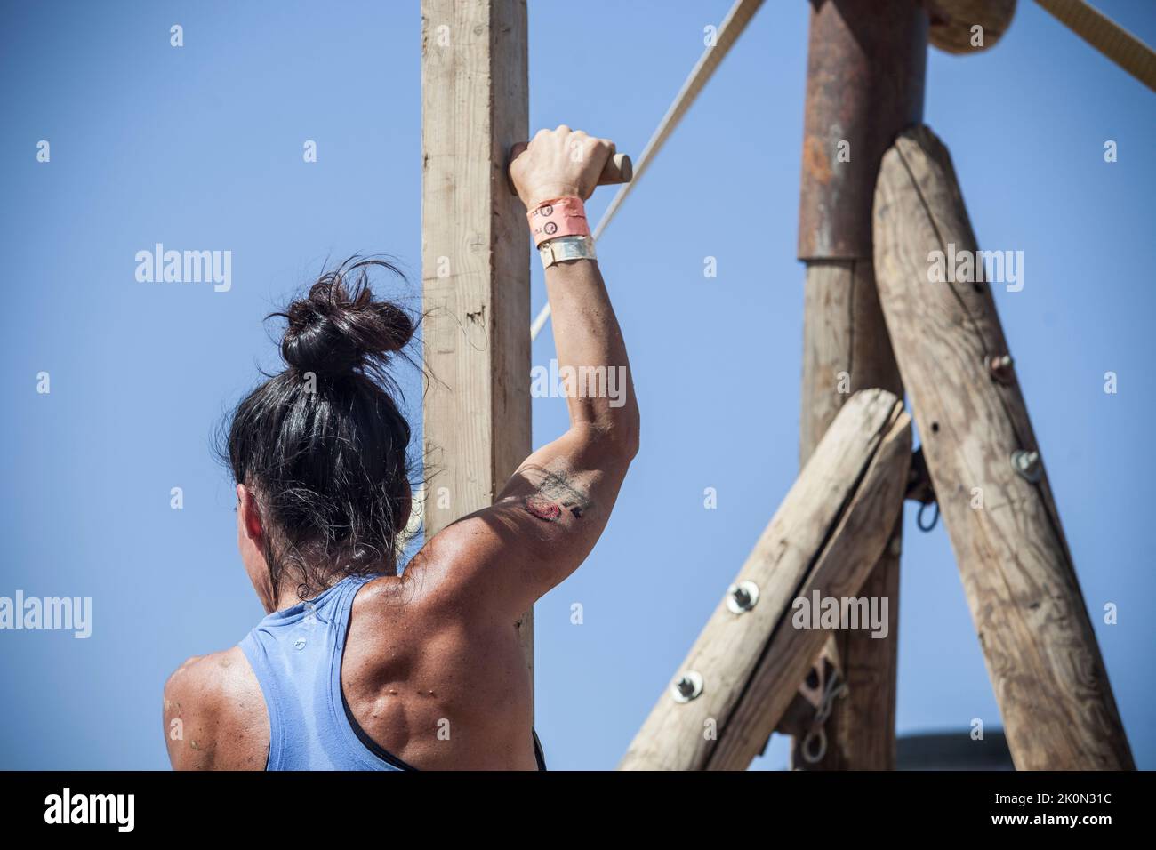 Merida, Spain - Sept 11th, 2022: FarinatoRace Merida 2022. Toughest obstacle course in the world. Woman climbing up a wooden beam with spikes Stock Photo