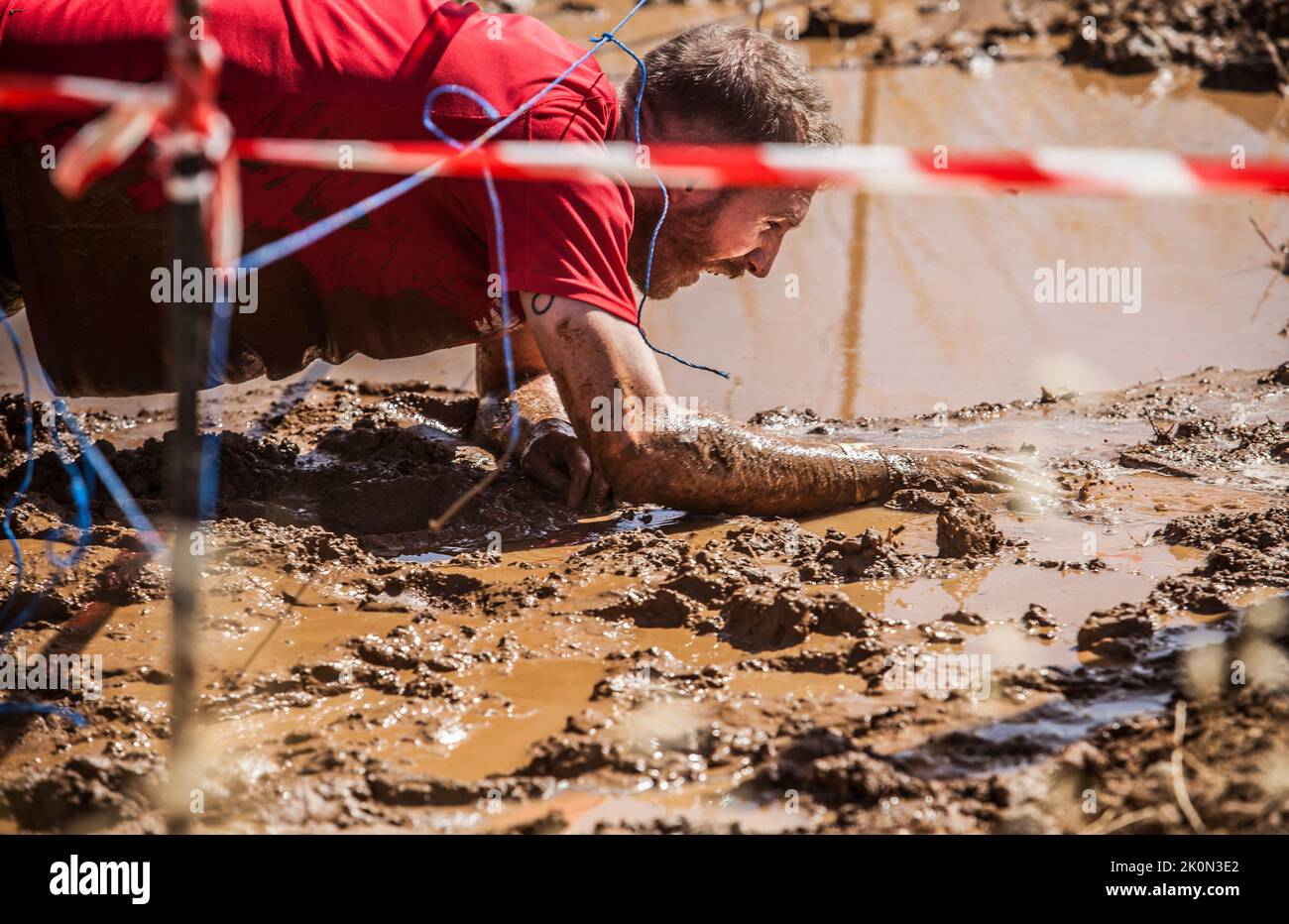Merida, Spain - Sept 11th, 2022: FarinatoRace Merida 2022. Toughest obstacle course in the world. Crawling under wire Stock Photo