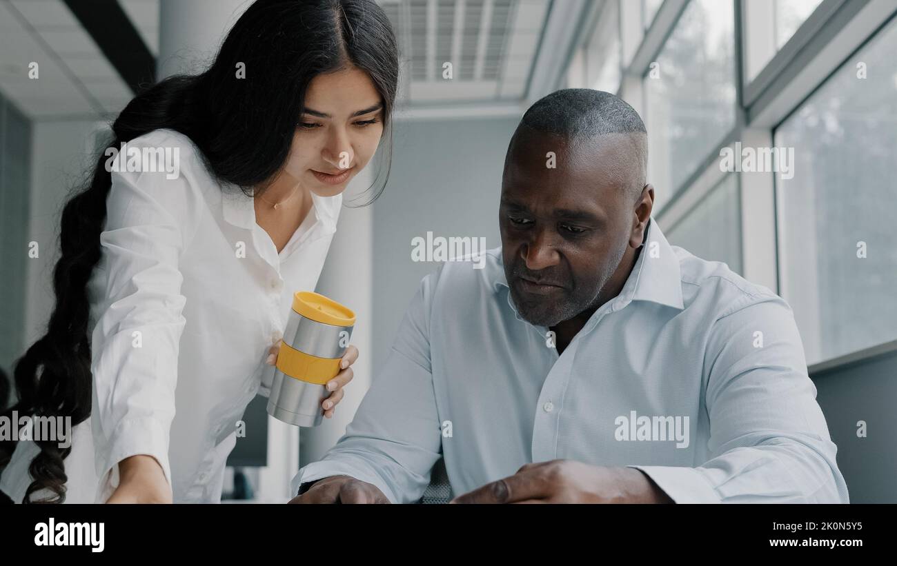 Two colleagues business partners office co-workers analyze paperwork check information. Arabian woman check documentation papers report help african Stock Photo
