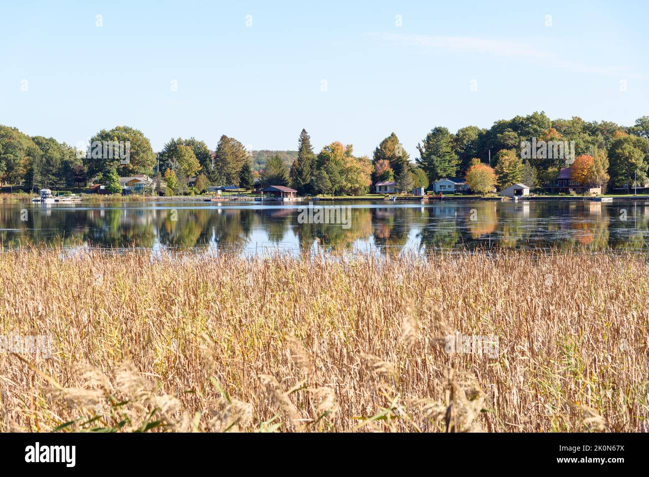 Riverside holiday houses on the wooded bank of a river on a sunny autumn day, Reflection in water. Thousand Islands National Park, ON, Canada. Stock Photo