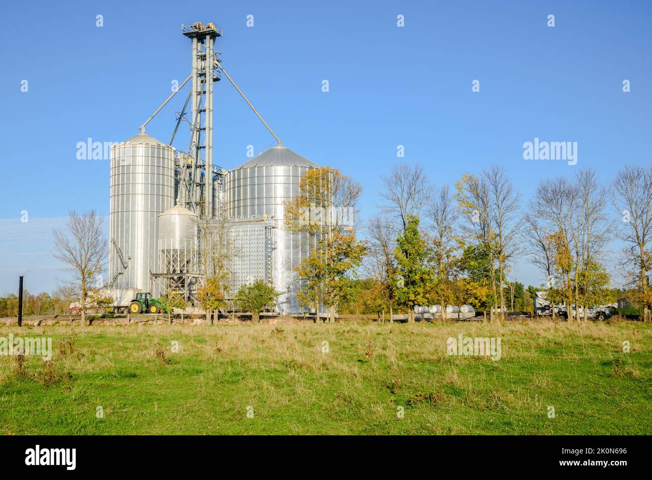 View of a grain elevator with large steel storage bins in the countryside under clear sky at sunset Stock Photo