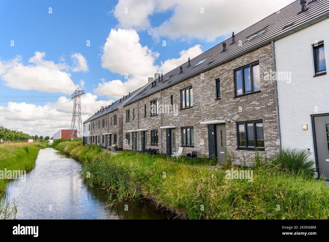 Row of new brick terraced houses along a canal in a suburban housing development on a sunny summer day Stock Photo