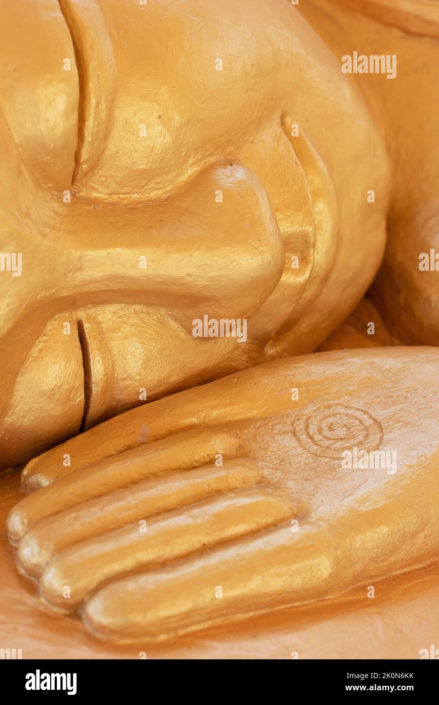 Close up of the face and hand of a gold sleeping Buddha statue, at Watt Munisotaram Cambodian Buddhist Monastery in Hampton, Minnesota. Stock Photo