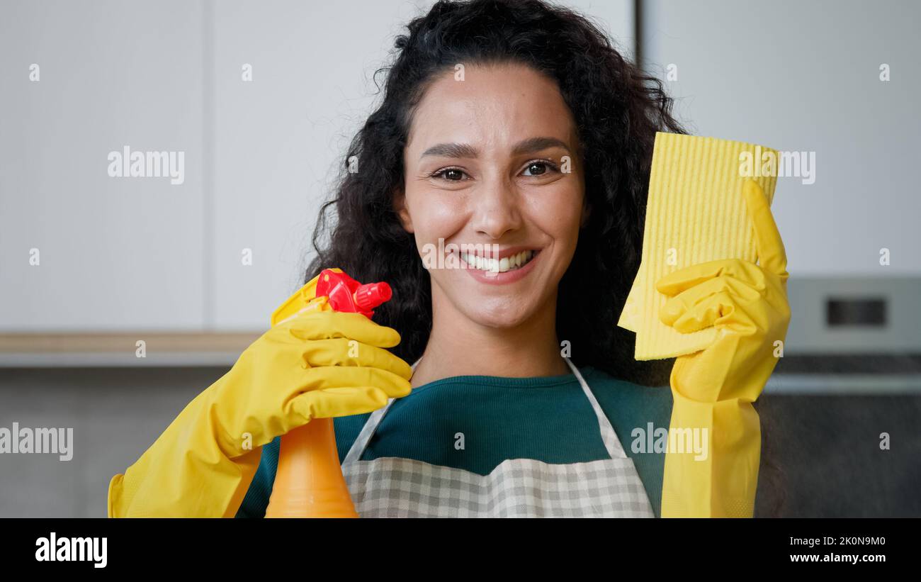 Happy young housewife mistress female maid worker housekeeper mother wife posing in kitchen wears yellow rubber protective gloves hold cleanser bottle Stock Photo
