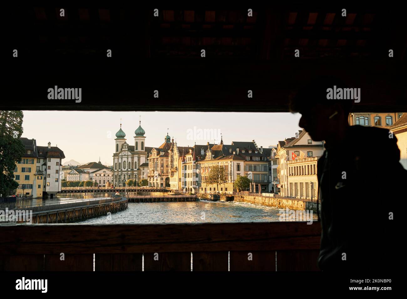 Anonymous man strolling on footbridge over river in old city Stock Photo