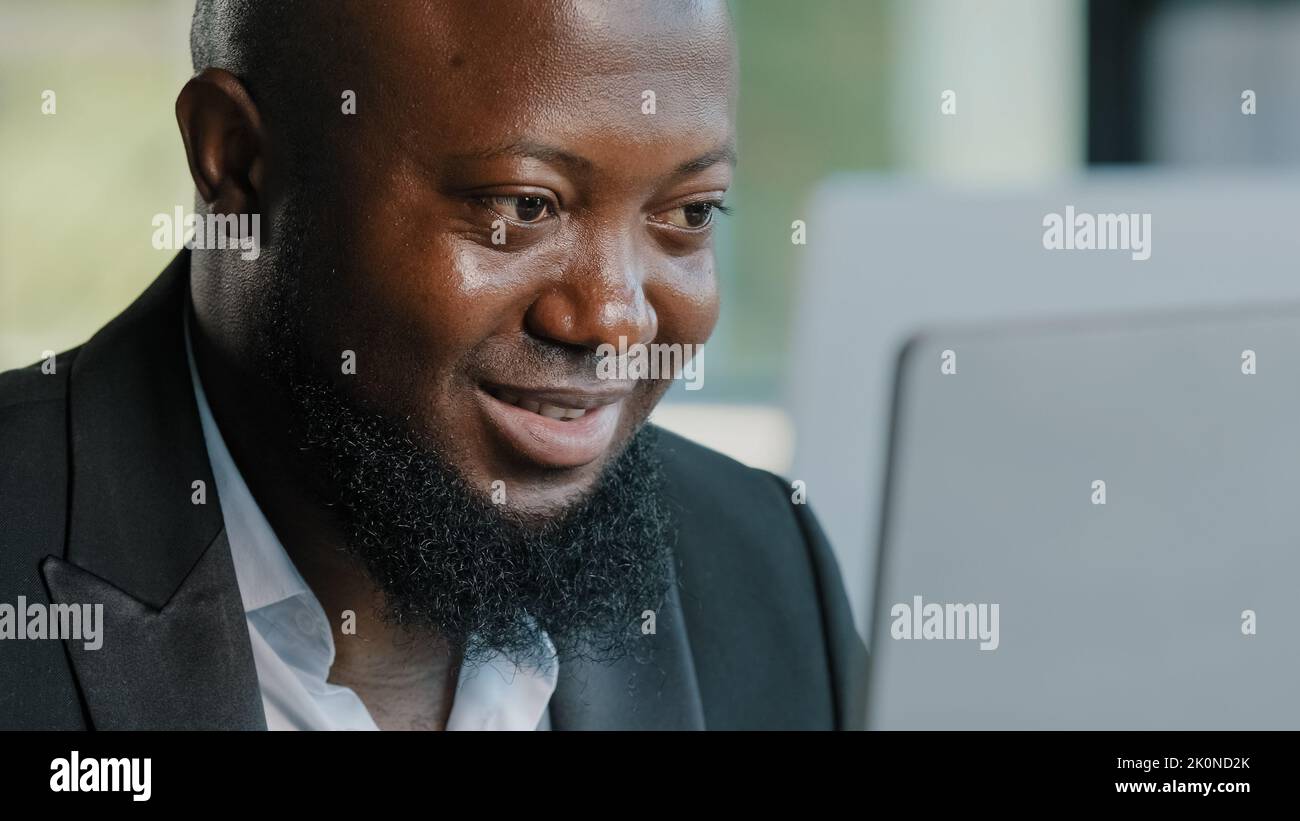 Close up male worker african american man bearded businessman guy employee specialist work on laptop in office space chatting with colleagues typing Stock Photo