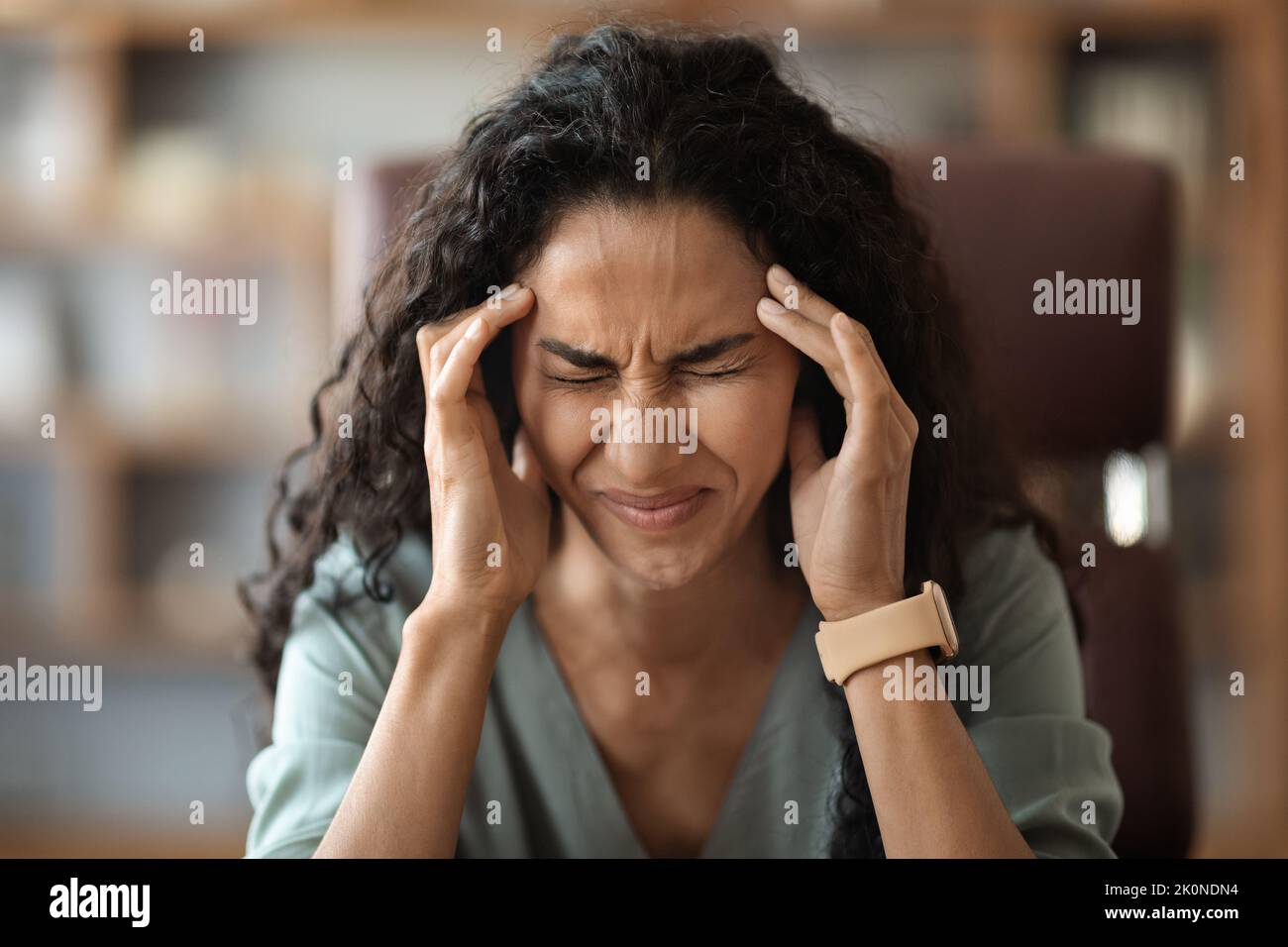 Unhappy young lady suffering from migraine while working Stock Photo