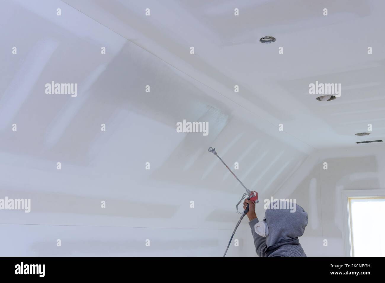 The worker using spray gun with a primer paint walls and ceiling Stock