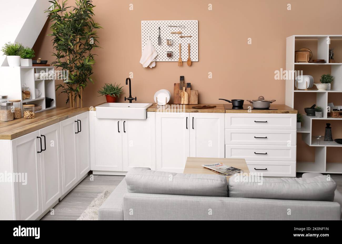 Interior of stylish kitchen with white counters, utensils and pegboard ...