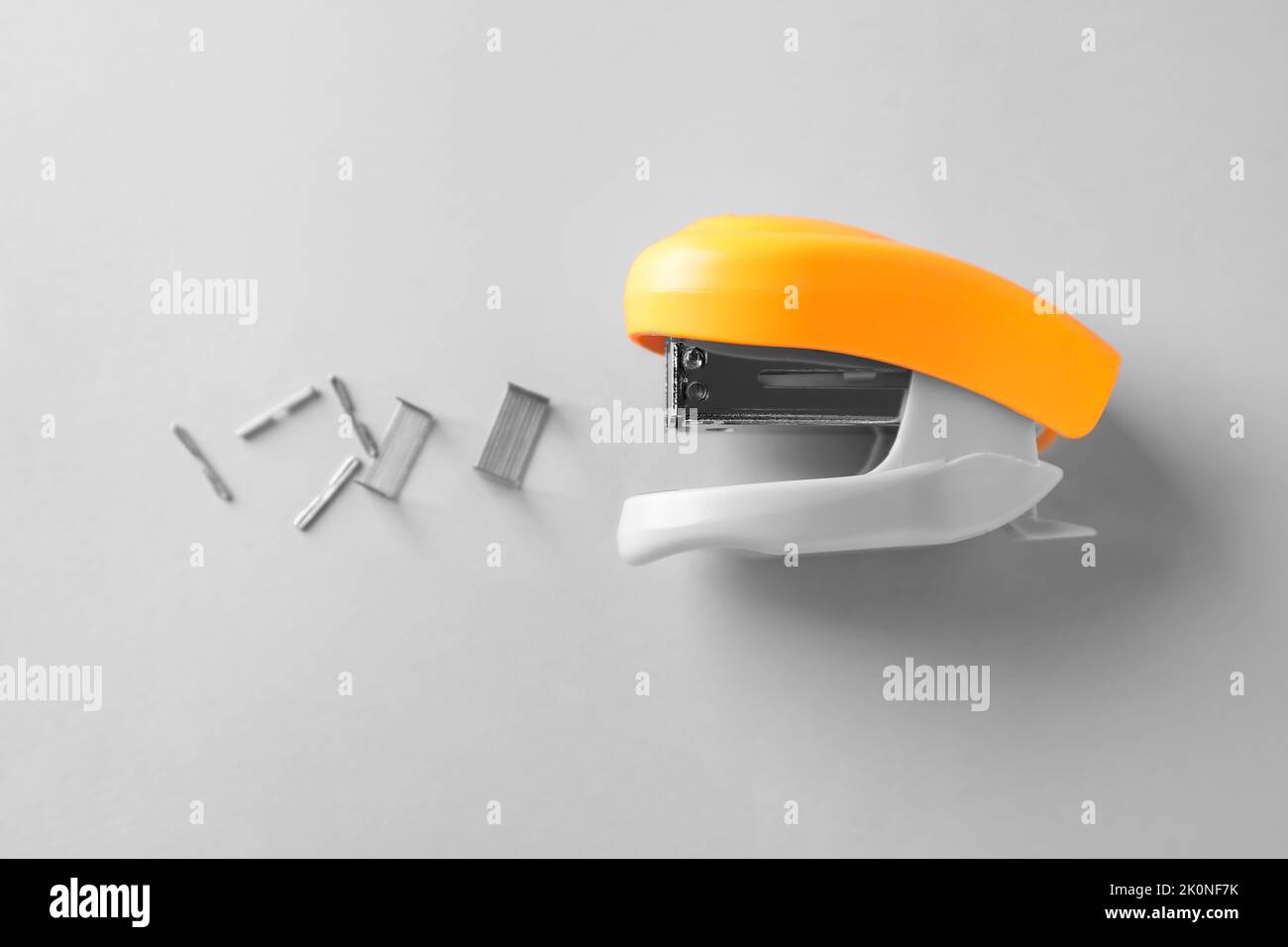 Orange stapler with staples on white background Stock Photo Alamy