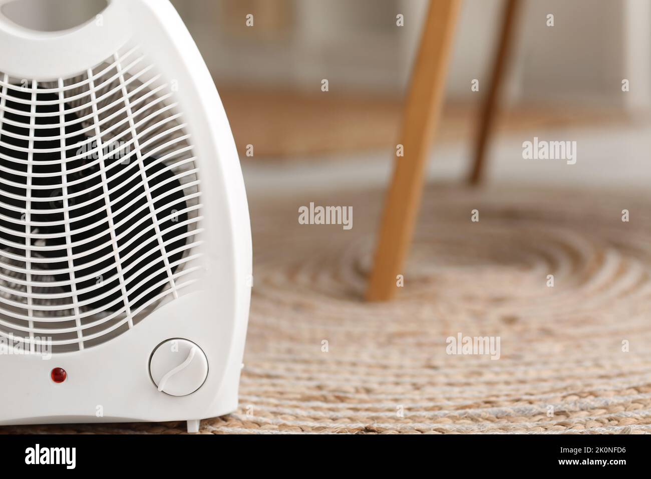Electric fan heater on rug in living room, closeup Stock Photo